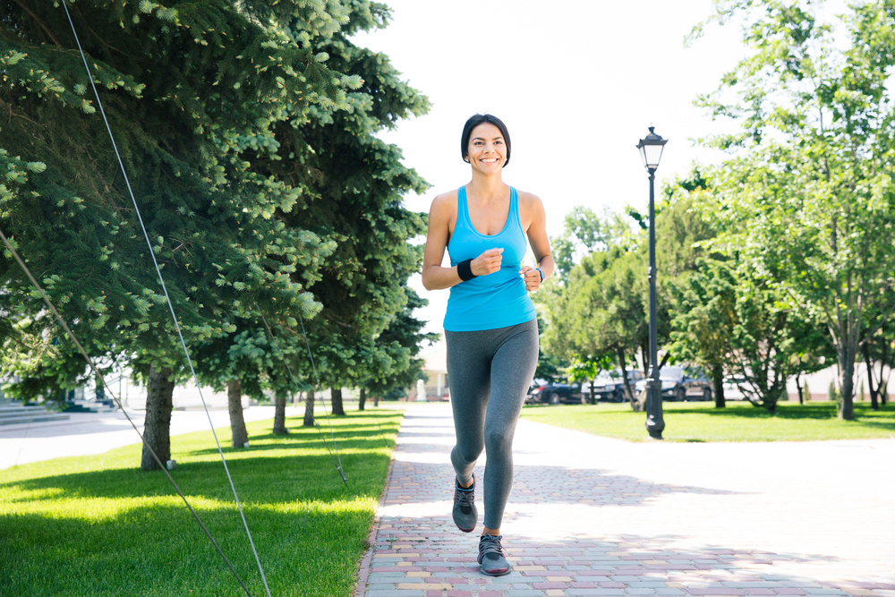 Full length portrait of a happy sports woman running outdoors