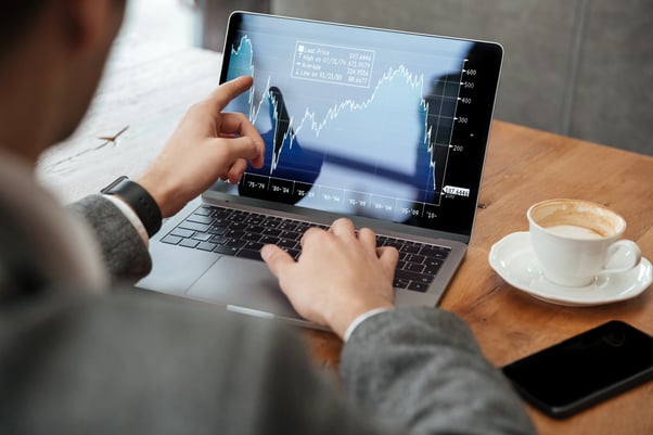 imagen-recortada-del-empresario-sentado-junto-la-mesa-en-la-cafeteria-y-analizar-indicadores-en-la-computadora-portatil